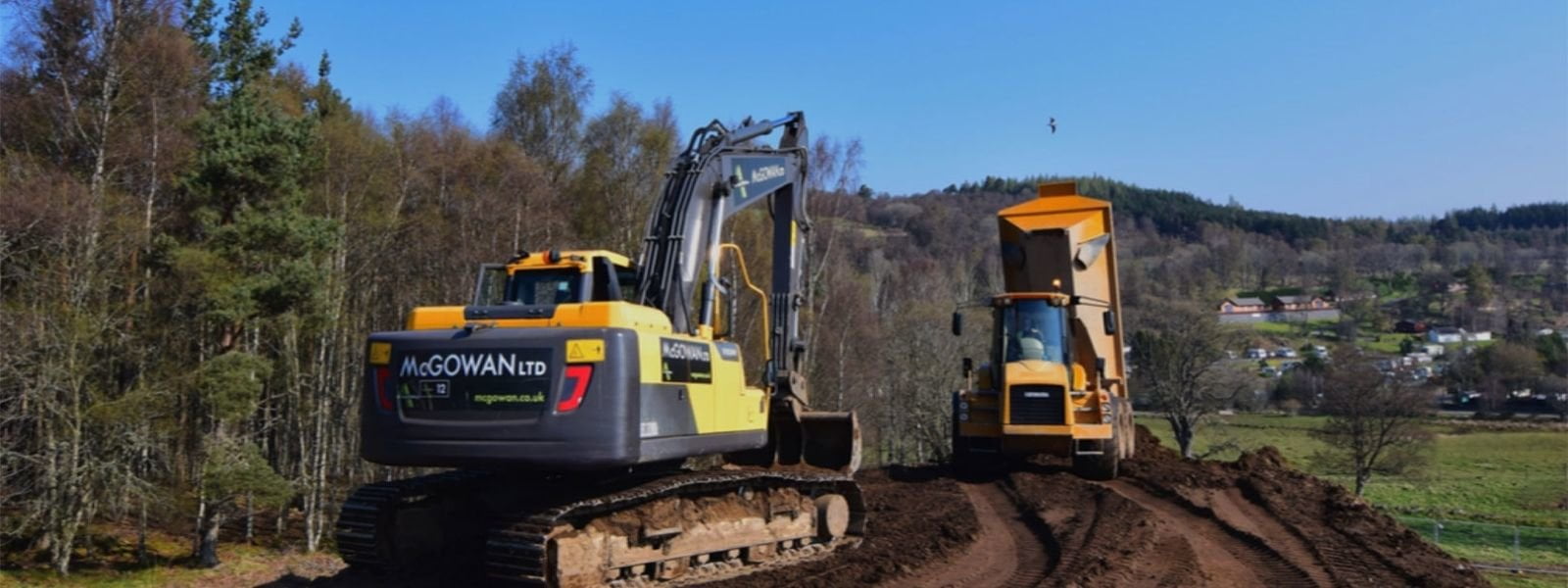 Photograph showing earth digger and truck undertaking site preparation, courtesy of McGowan Engineering.