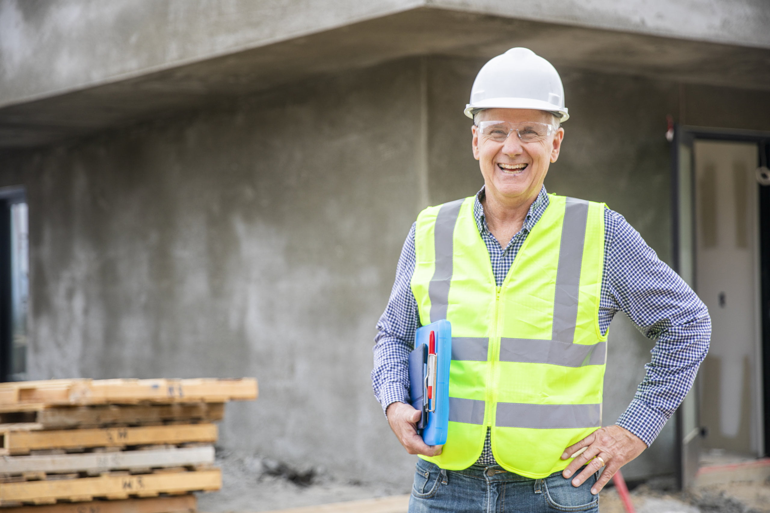 Photograph of a lone working senior construction site manager visually inspecting a building project.