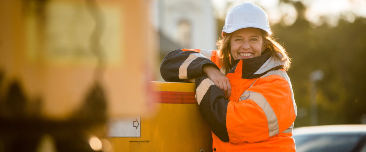 Photograph of female engineer lone working outdoors wearing protective workwear.