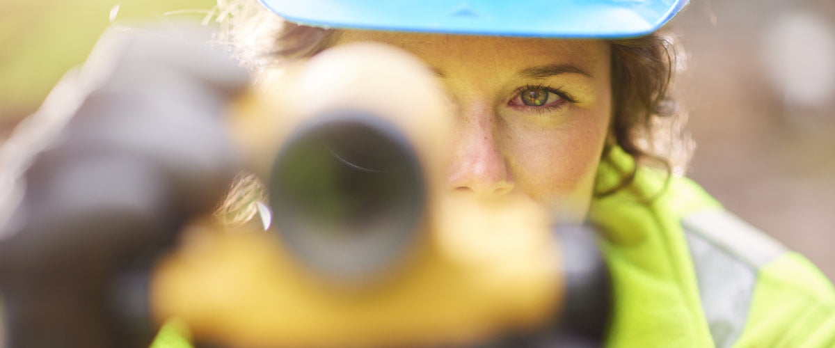 Photograph of lone working female surveyor using a theodolite.