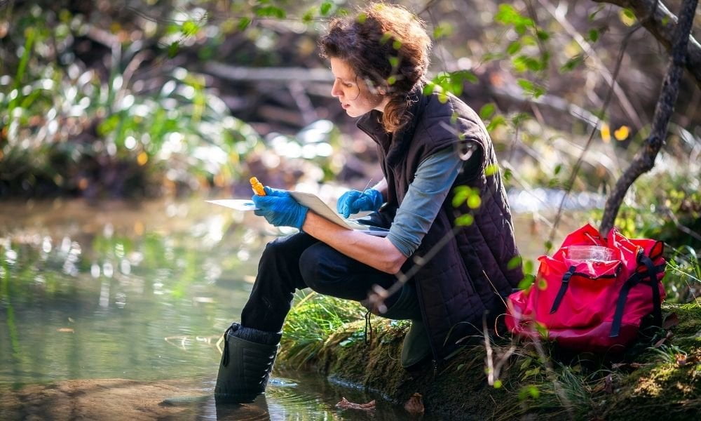 Photograph of lone working female biologist working by a river.