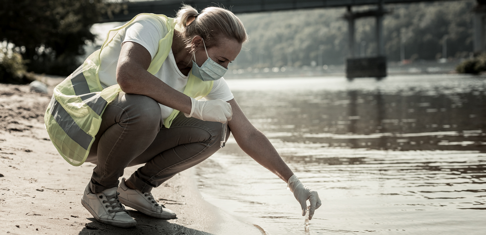 Image of lone working water inspector sampling water in a river